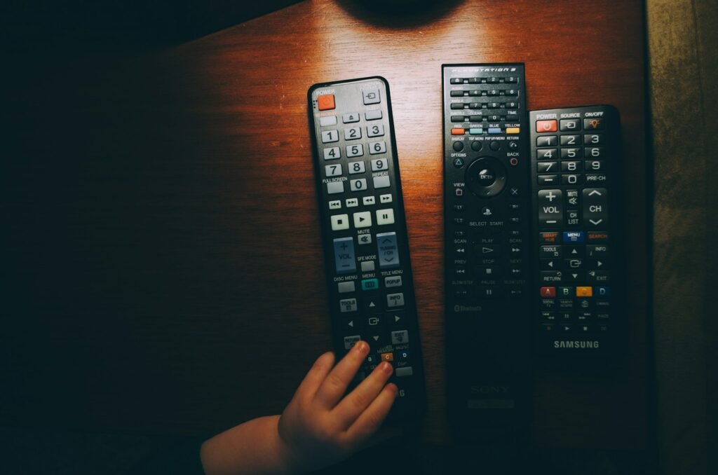 Three remote controls on a wooden table illustrating television account setup